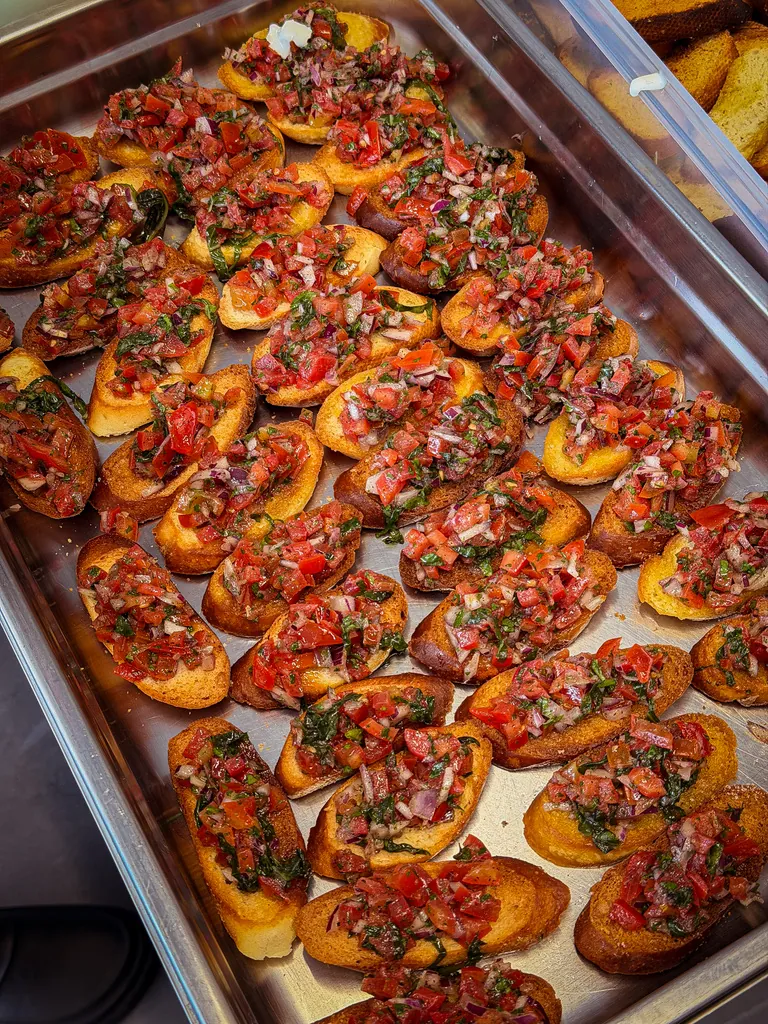 Tray of bruschetta topped with diced tomato, red onion and herbs