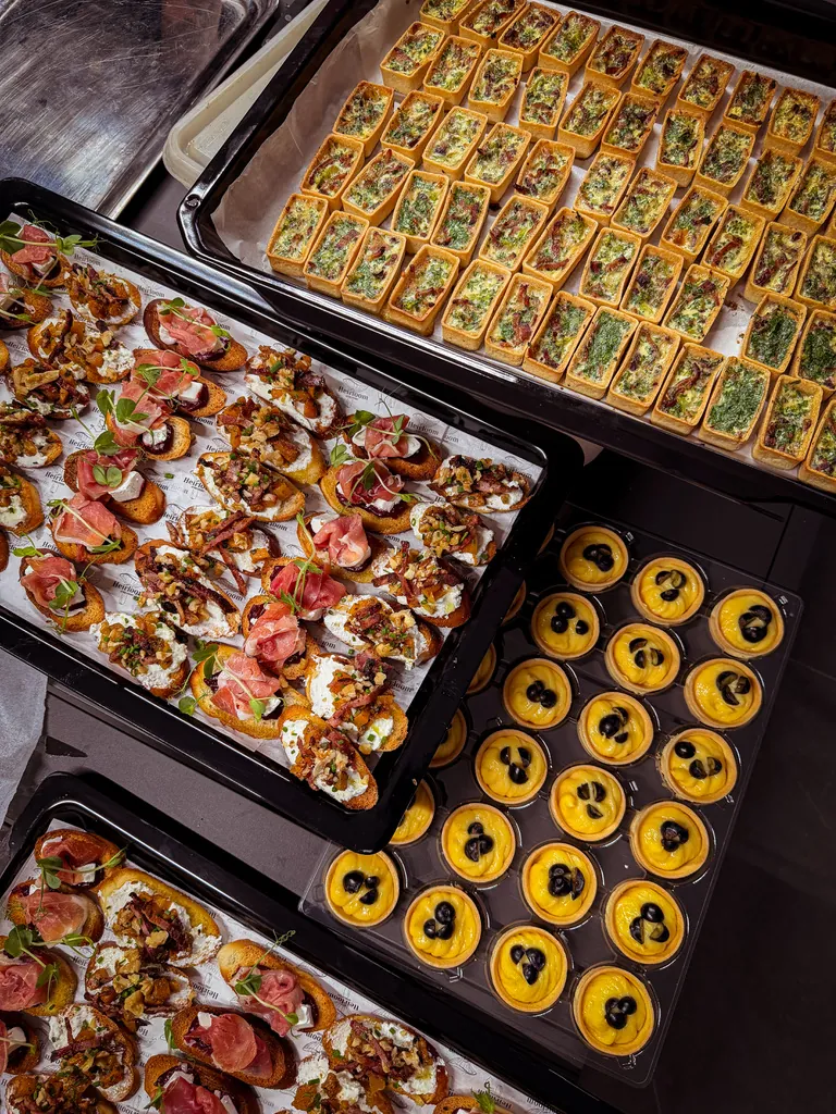 Event trays of cured ham crostini, herb quiche squares and mini tartlets